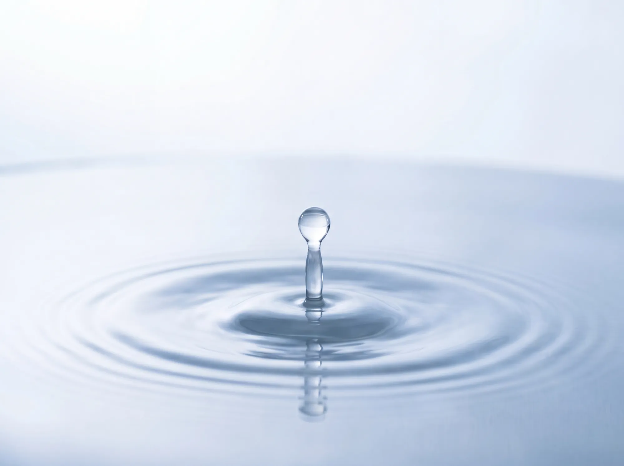 A water droplet creating concentric ripples on a still surface